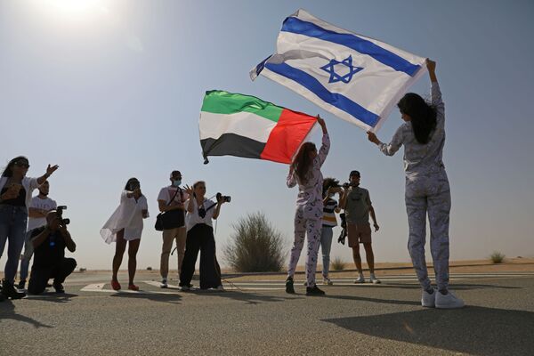 İsrail bayrağını omzunda taşıyarak Dubai'nin çöl bölgelerinde poz veren Tager'e, burada ikamet eden Rus Anastasia Bandarenka de BAE bayrağı ile eşlik etti.  - Sputnik Türkiye
