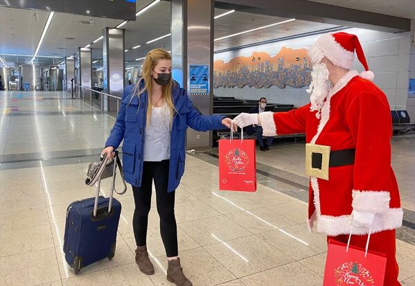 Noel baba kostümlü animatör, gelen yolculara mutlu yıllar dileyerek hediye paketleri takdim etti. - Sputnik Türkiye