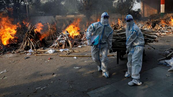 Hindistan başkenti Yeni Delhi'de Kovid-19 kurbanlarının yakıldığı krematoryuma odun taşıyan koruma kıyafetli sağlık çalışanları - Sputnik Türkiye