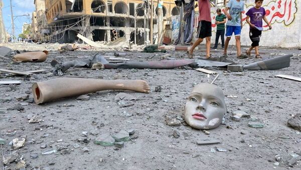 Gazze'de İsrail'in hava saldırılarında zarar gören bir binanın yakınlarında yola savrulmuş cansız manken parçaları - Sputnik Türkiye