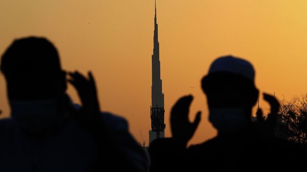 На фоне самого высокого здания в мире, Бурдж-Халифа, мусульманские мужчины в масках молятся, Дубай - Sputnik Türkiye