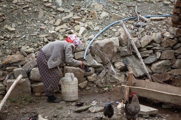 Çamur deryasına dönen köyde bir kadın, az miktarda akan suyun altında ayakkabısını temizlemeye çalışıyor.
 - Sputnik Türkiye
