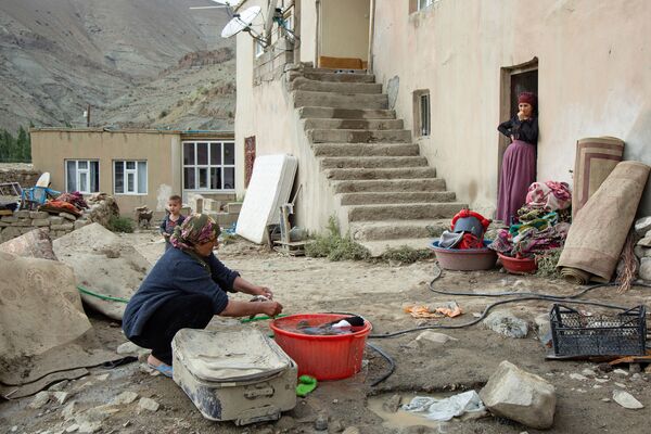 Kadınlar, çamur içinde kalan evlerinden kullanılabilecek eşyalarını çıkararak temizliyor.
 - Sputnik Türkiye