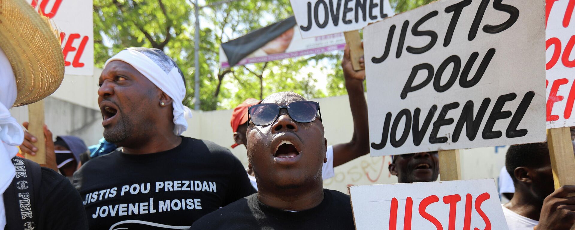 ABD destekli darbeyle öldürülen Haiti Devlet Başkanı Jovenel Moise suikastıyla ilgili davanın görüldüğü başkent Port-au-Prince'deki mahkeme önünde 'Jovenel için adalet' pankartları açan göstericiler  - Sputnik Türkiye, 1920, 17.10.2021