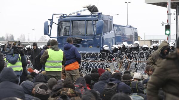 Мигранты перед забором из колючей проволоки на блокпосту «Кузница» на белорусско-польской границе - Sputnik Türkiye