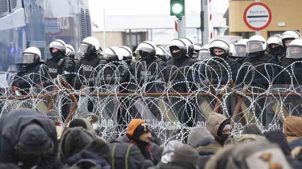 Мигранты перед забором из колючей проволоки на блокпосту «Кузница» на белорусско-польской границе - Sputnik Türkiye