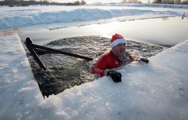 Yerel bir kış yüzme kulübünün üyeleri, Rusya&#x27;nın Tomsk kentinin dışındaki Boyarskoye gölünün buzlu sularında Noel şenliği düzenledi. - Sputnik Türkiye