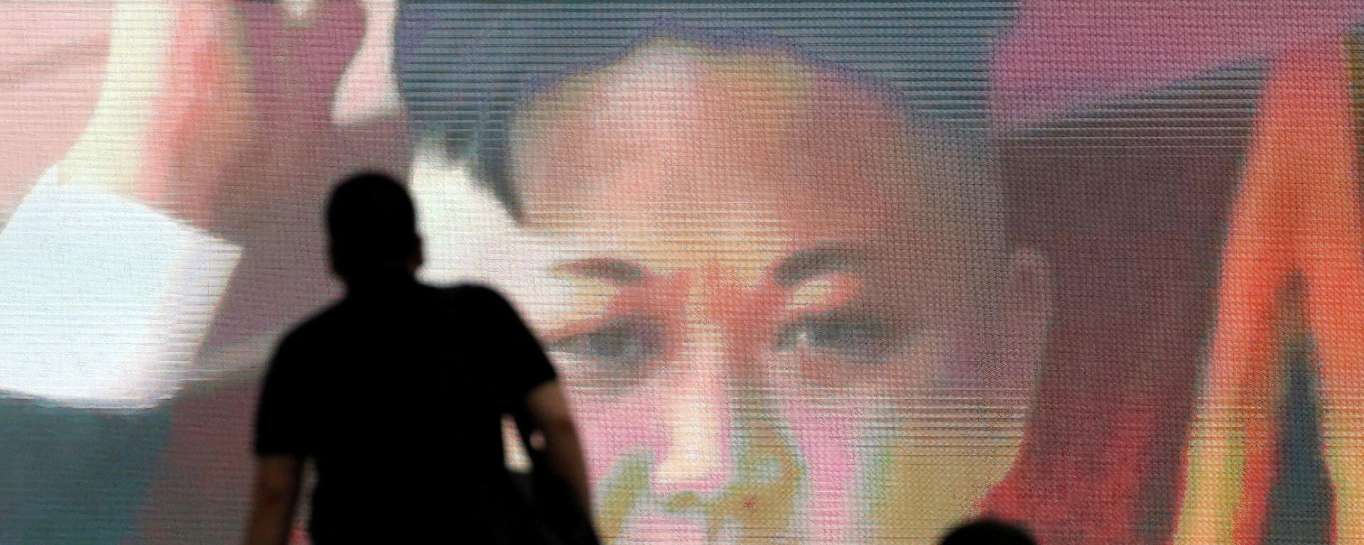 Kuzey Kore'nin 4 Temmuz 2017'deki uzun menzilli kıtalararası balistik füze denemesiyle ilgili Tokyo'daki monitörlerden akan ve Kuzey Kore lideri Kim Jong-un'u gösteren görüntüler önünden yürüyen Japonlar - Sputnik Türkiye, 1920, 17.11.2022