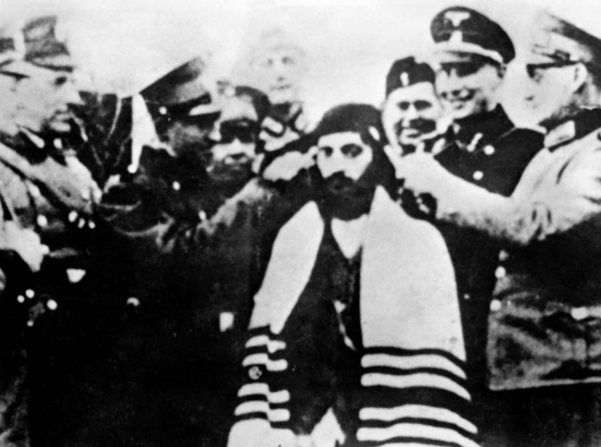 Nazi lideri ve savaş suçlusu Adolf Eichmann, Bergen-Belsen toplama kampında Alman subaylar bir Yahudi mahkumun saç buklelerini keserken gülümsüyor. - Sputnik Türkiye, 1920, 16.03.2022