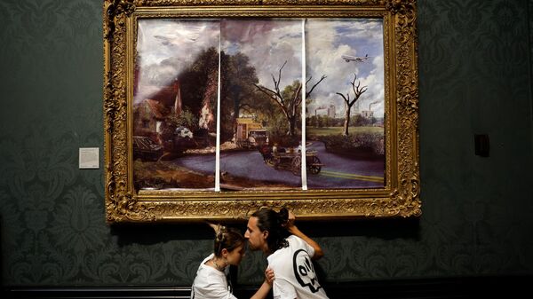 İngiltere’nin başkenti Londra’da bulunan Ulusal Galeri’ye gelen iki iklim aktivisti, ellerini sürdükleri yapıştırıcı ile John Constable’ın 1821 tarihli eseri The Hay Wain’in (Saman Arabası) çerçevesine yapıştırdılar.  - Sputnik Türkiye