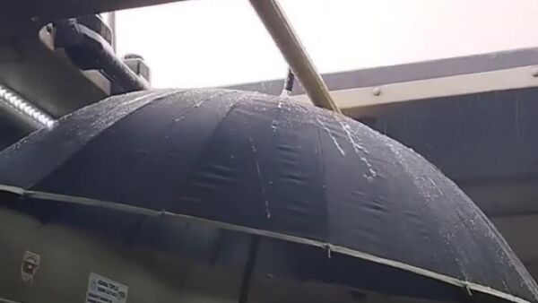 Adana’da dolmuş şoförü havalandırmayı açık bırakınca bir kadın yolcunun yağan yağmurdan korunmak için araç içinde şemsiye açtı. - Sputnik Türkiye