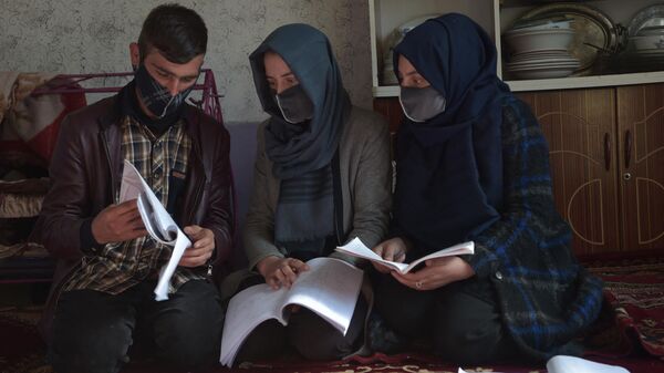 Afganistan'da ailesinin üniversitede okuyacak ilk kadın üyesi olmaya hazırlanırken Taliban'ın kadınlara yüksek eğitim yasağına çarpan Merve (ortada), üniversite eğitimi alabilen erkek kardeşi Hamid ile birlikte evde kitap okurken - Sputnik Türkiye