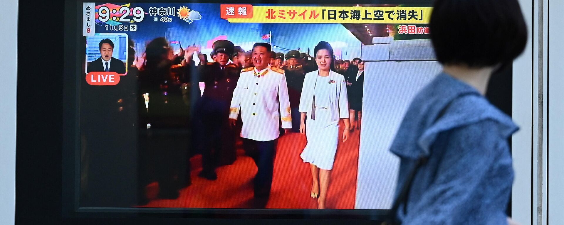 Kuzey Kore lideri Kim Jong-un ile eşi Ri Sol-ju'nun ekrandaki görüntülerine bakan Japonya'nın başkenti Tokyo'daki yayalar  - Sputnik Türkiye, 1920, 08.02.2023