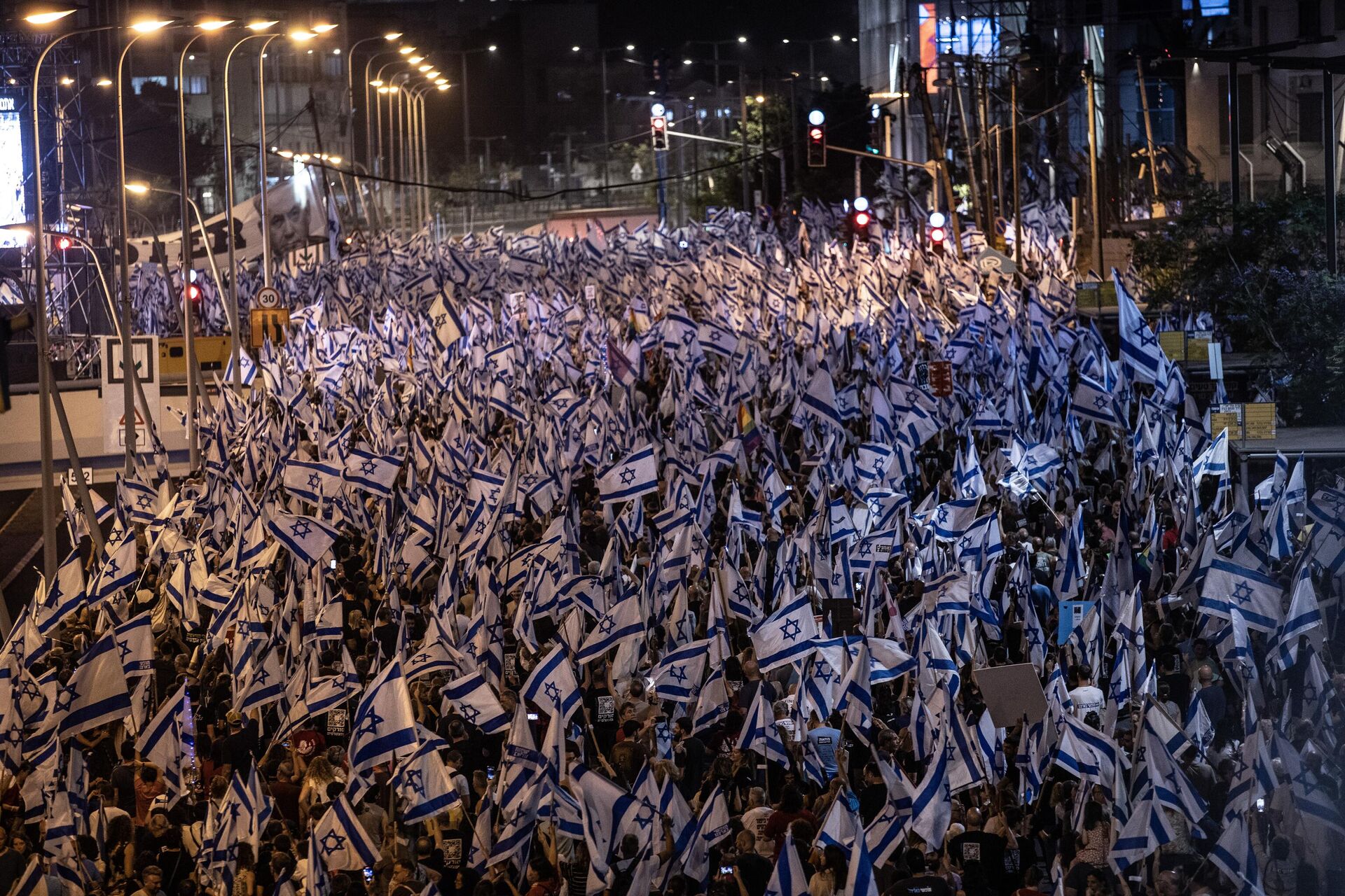 İsrailliler, Başbakan Benyamin Netanyahu öncülüğündeki koalisyon hükümetinin yargının yetkililerini sınırlayan düzenlemesine ve sağ politikalarına yönelik protestolarına devam ediyor. Tel Aviv'de binlerce protestocu, ellerinde İsrail bayraklarıyla sık sık demokrasi sloganları atarak koalisyon hükümetindeki aşırı sağcı politikacıları eleştiren dövizler taşıdı.  - Sputnik Türkiye, 1920, 27.05.2023