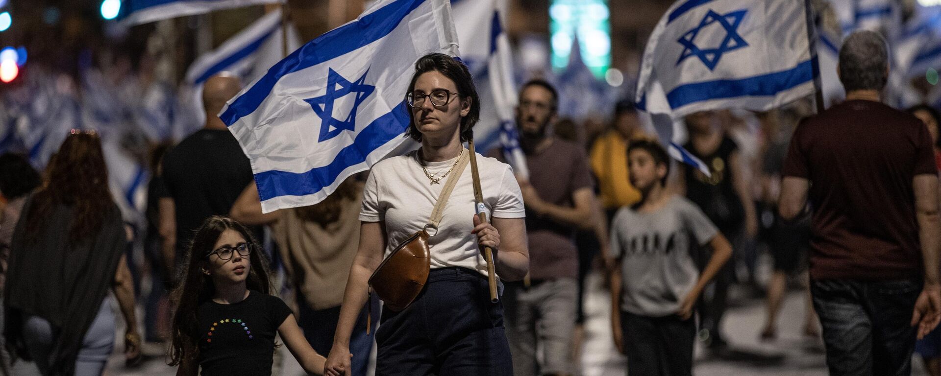 İsrailliler, Başbakan Benyamin Netanyahu öncülüğündeki koalisyon hükümetinin yargının yetkililerini sınırlayan düzenlemesine ve sağ politikalarına yönelik protestolarına devam ediyor. Tel Aviv'de binlerce protestocu, ellerinde İsrail bayraklarıyla sık sık demokrasi sloganları atarak koalisyon hükümetindeki aşırı sağcı politikacıları eleştiren dövizler taşıdı.  - Sputnik Türkiye, 1920, 09.07.2023