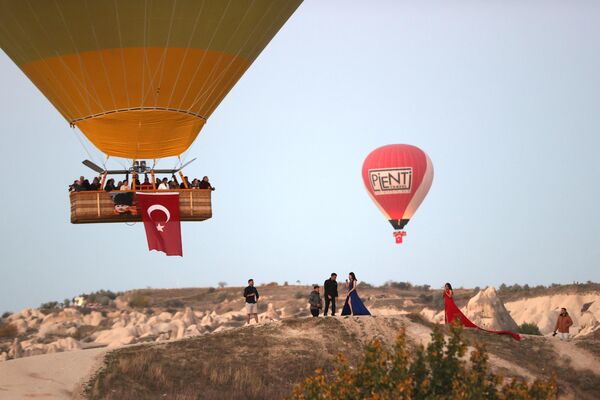 Türk bayrağı ve Atatürk posteri taşıyan balonlar, peribacalarıyla kaplı  vadiler üzerinde uçarken, turistler de ortaya çıkan manzarada fotoğraf  çektirdi. - Sputnik Türkiye