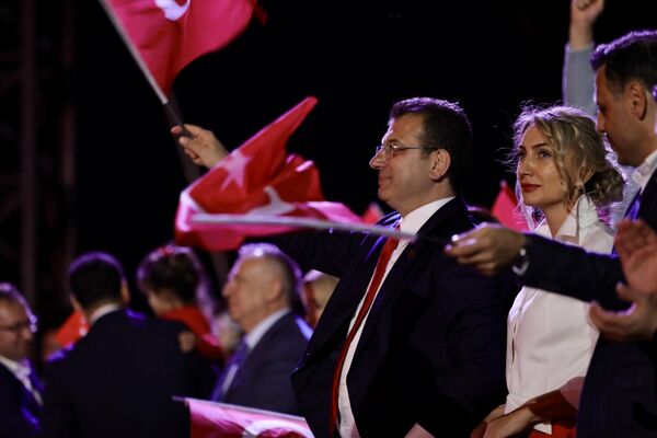 İmamoğlu çifti ve çalışanlar, karşılıklı sıraya dizilerek dev bir Türk bayrağını, sahne üzerinde çekileceği göndere elden ele ulaştırdı. - Sputnik Türkiye