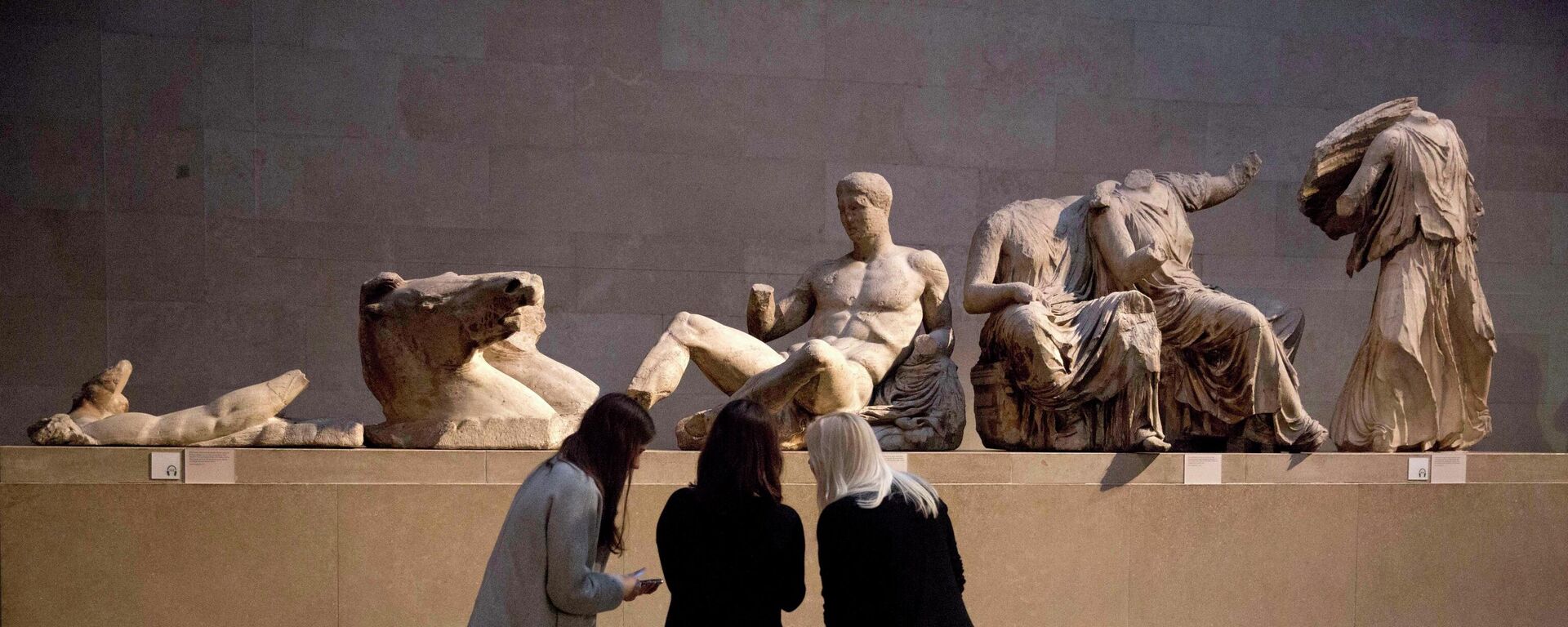 Women look at a statue of the Greek god Dionysus, part of the Parthenon Marbles - Sputnik Türkiye, 1920, 31.07.2025