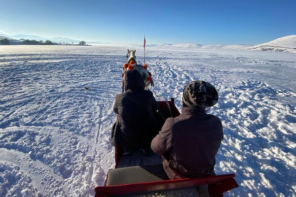 Gölün, Ardahan tarafındaki kıyı kesimlerine gelen yerli ve yabancı turistler, buzla kaplı göl üzerinde yürüyüş yapıp, atlı kızaklarla gezinti yapıyor. - Sputnik Türkiye