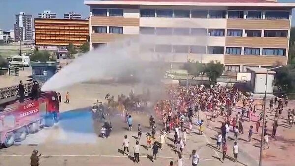 Osmaniye'nin Düziçi ilçesinde bir okulda düzenlenen şenlikte sıcak hava dolayısıyla bunalan öğrenciler, itfaiye tarafından su sıkılarak serinletildi. - Sputnik Türkiye