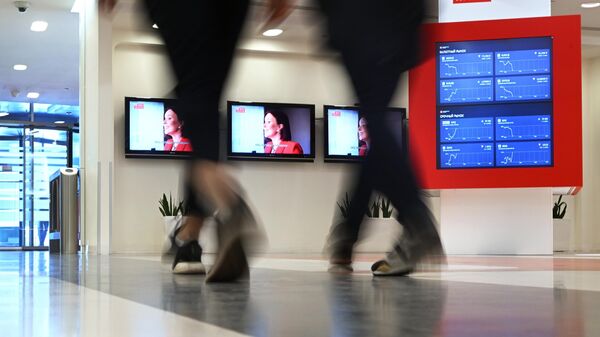 People walk past a screen showing currency exchange rates, share price index and other information is pictured in the office of the Moscow Exchange in Moscow, Russia. - Sputnik Türkiye