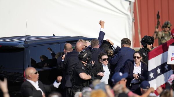 Дональда Трампа уводят в автомобиль после покушения на предвыборном митинге в Батлере, США - Sputnik Türkiye