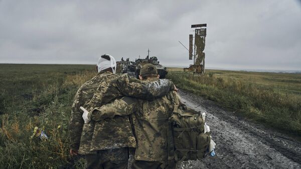 A Ukrainian soldier helps a wounded fellow. File photo - Sputnik Türkiye