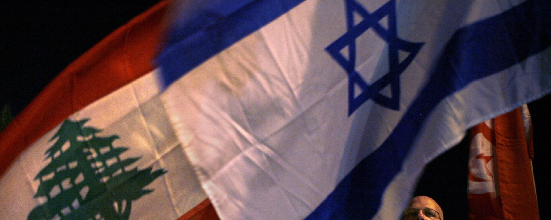 An Israeli left-wing activist holds an Israeli flag next to a Lebanese flag during a rally by the group supporting the Saudi Peace Initiative outside the Prime Minister's residence in Jerusalem, Wednesday, March 28, 2007. Arab leaders opened a summit Wednesday to revive a plan for peace with Israel, with U.S. allies trying to enlist other Arabs in efforts to win Israeli and Western acceptance of the deal. The initiative, first launched by the Arab summit in 2002, offers Israel recognition and permanent peace with all Arab countries in return for Israeli withdrawal from lands captured in the 1967 Mideast war.(AP Photo/Kevin Frayer) - Sputnik Türkiye, 1920, 27.11.2024