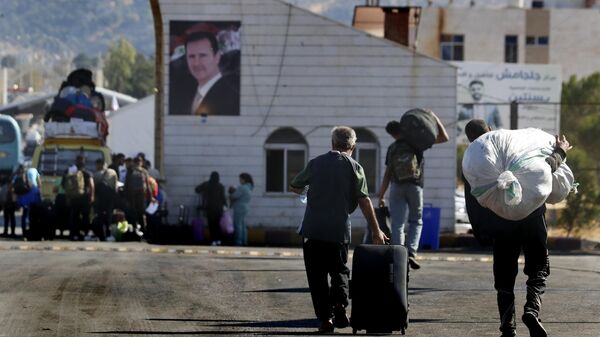 Syrians who fled the war in Lebanon carry their belongings as they arrive at the Syrian border crossing point, in Jdeidet Yabous, Syria, Monday, Oct. 7, 2024. (AP Photo/Omar Sanadiki) - Sputnik Türkiye