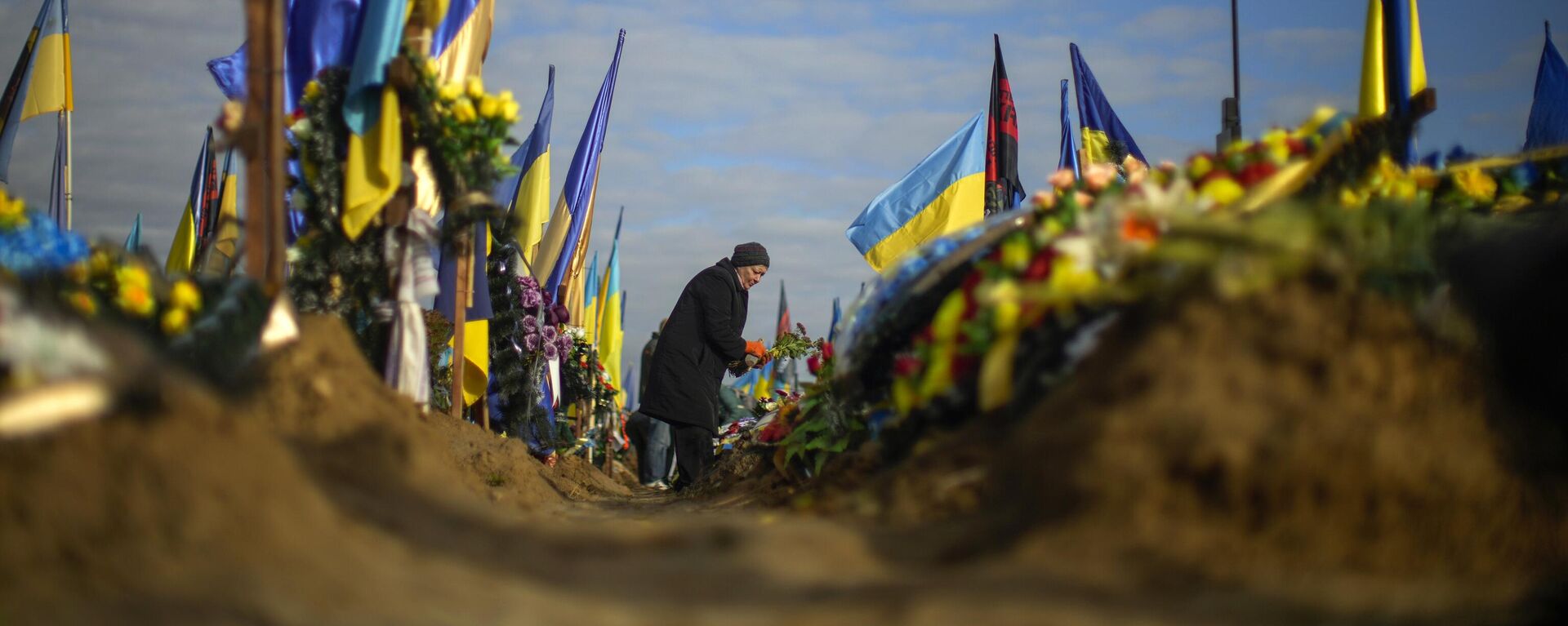 Olga places flowers on the grave of a relative recently killed on military duty, in a cemetery during Ukraine Defenders Day in Kharkiv, Ukraine, Friday, Oct. 14, 2022. (AP Photo/Francisco Seco) - Sputnik Türkiye, 1920, 17.12.2024