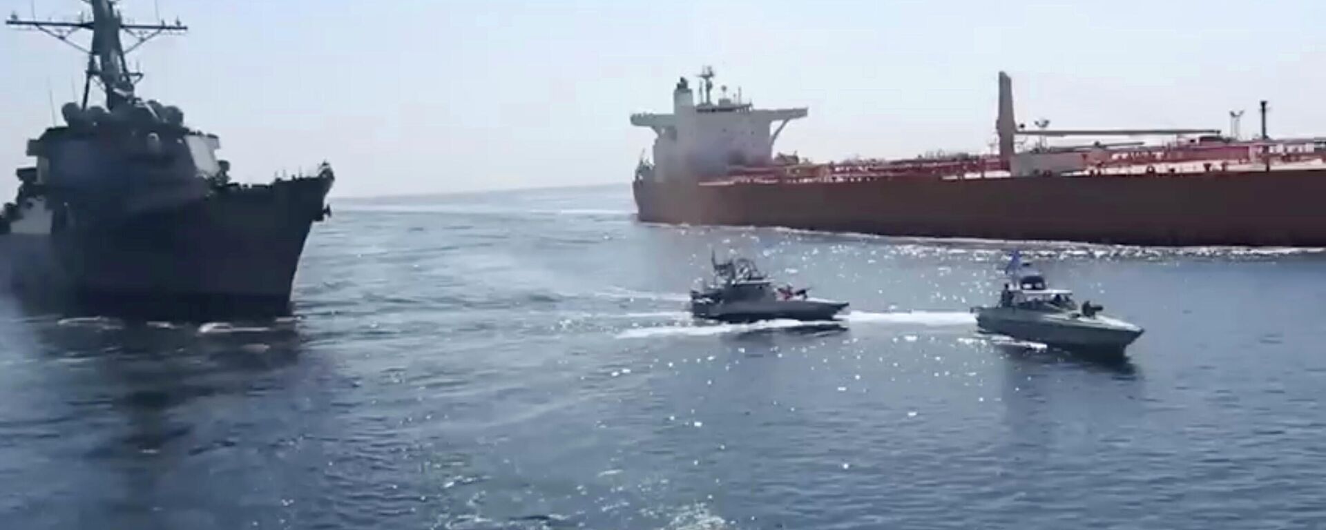 This frame grab from a video released by Iran's paramilitary Revolutionary Guard on Wednesday, Nov. 3, 2021, shows the Guard speed boats, center, in front of a U.S warship, left, amid the seizure of a Vietnamese-flagged oil tanker, right, in the Gulf of Oman. Iran seized the tanker in the Gulf of Oman last month and still holds the vessel, two U.S. officials told The Associated Press on Wednesday, revealing the latest provocation in Mideast waters as tensions escalate between Iran and the United States over Tehran's nuclear program. (Revolutionary Guard via AP) - Sputnik Türkiye, 1920, 08.04.2025