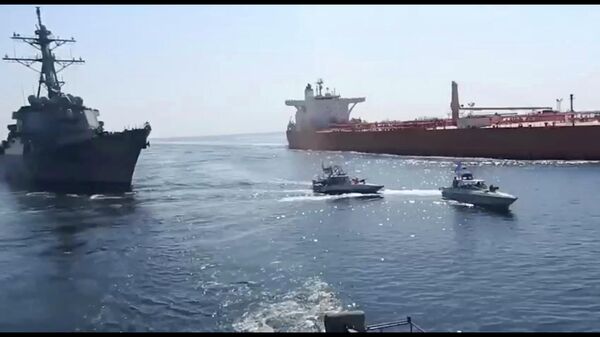 This frame grab from a video released by Iran's paramilitary Revolutionary Guard on Wednesday, Nov. 3, 2021, shows the Guard speed boats, center, in front of a U.S warship, left, amid the seizure of a Vietnamese-flagged oil tanker, right, in the Gulf of Oman. Iran seized the tanker in the Gulf of Oman last month and still holds the vessel, two U.S. officials told The Associated Press on Wednesday, revealing the latest provocation in Mideast waters as tensions escalate between Iran and the United States over Tehran's nuclear program. (Revolutionary Guard via AP) - Sputnik Türkiye