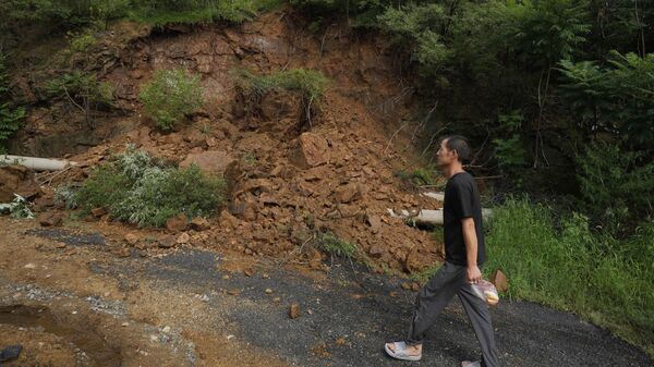 A man walks past a landslide after heavy rain in Miyun district on the outskirts of Beijing, China, Monday, July 28, 2025. - Sputnik Türkiye