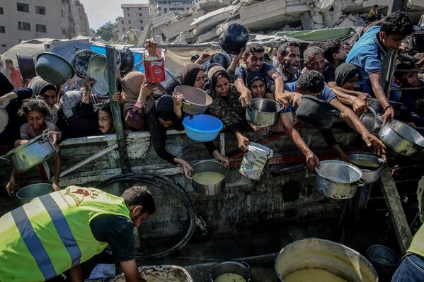 Gazze kentinde bir hayır kurumu tarafından düzenlenen yemek dağıtımı sırasında yoğun kalabalıklar oluştu. İnsanlar saatlerce sırada bekledi. - Sputnik Türkiye