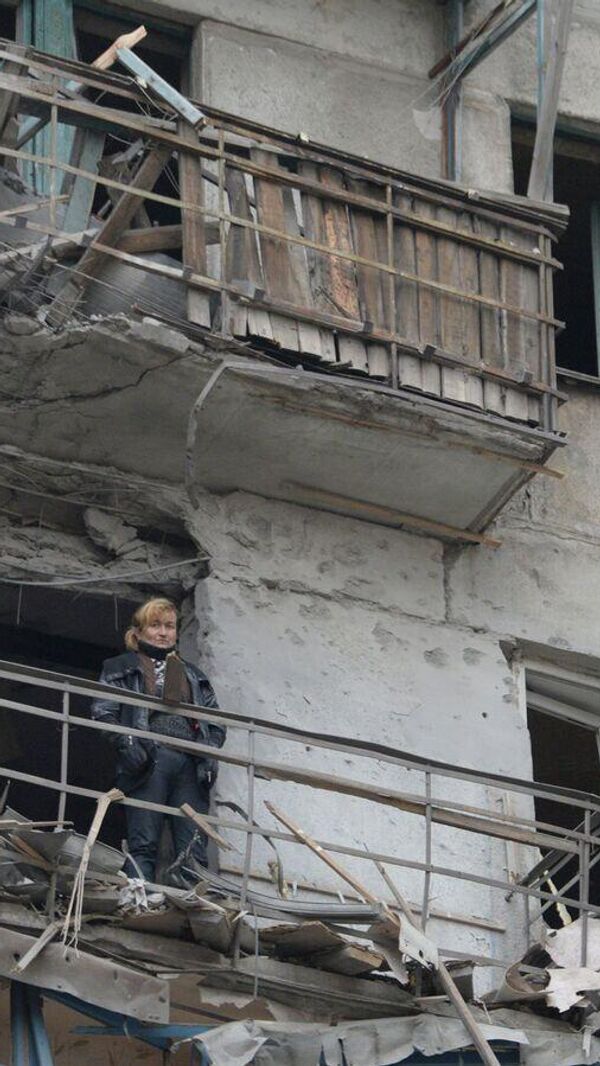 Bombalanan bir evin balkonunda duran kadın. - Sputnik Türkiye