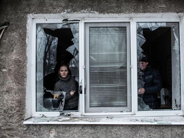 Bir kadın, Ukrayna ordusunun Donetsk merkezindeki Voroşilov&#x27;a düzenlediği topçu saldırısı sonucu hasar gören dairesinin kırık penceresinden bakıyor. - Sputnik Türkiye