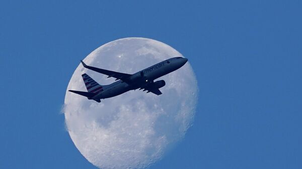 An American Airlines Boeing 737 flies past the moon as it heads to Orlando, Fla., after having taken off from Miami International Airport, Tuesday, April 19, 2022, in Miami. The major airlines and many of the busiest airports rushed to drop their requirements on Monday after a Florida judge struck down the CDC mandate and the Transportation Security Administration announced it wouldn't enforce its 2021 security directive.  - Sputnik Türkiye
