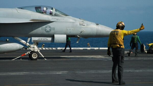 A crew member signals as a pilot prepares to launch an F/A-18 fighter jet on the deck of the USS Abraham Lincoln aircraft carrier in the Arabian Sea. File photo. - Sputnik Türkiye