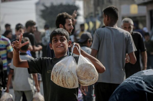 Gazze kentinin Rimal Mahallesi’nde toplanan onlarca Filistinli, Dünya Gıda Programı (WFP) desteğiyle üretim yapan fırınlardan cüzi bir ücret karşılığında ekmek aldı. - Sputnik Türkiye