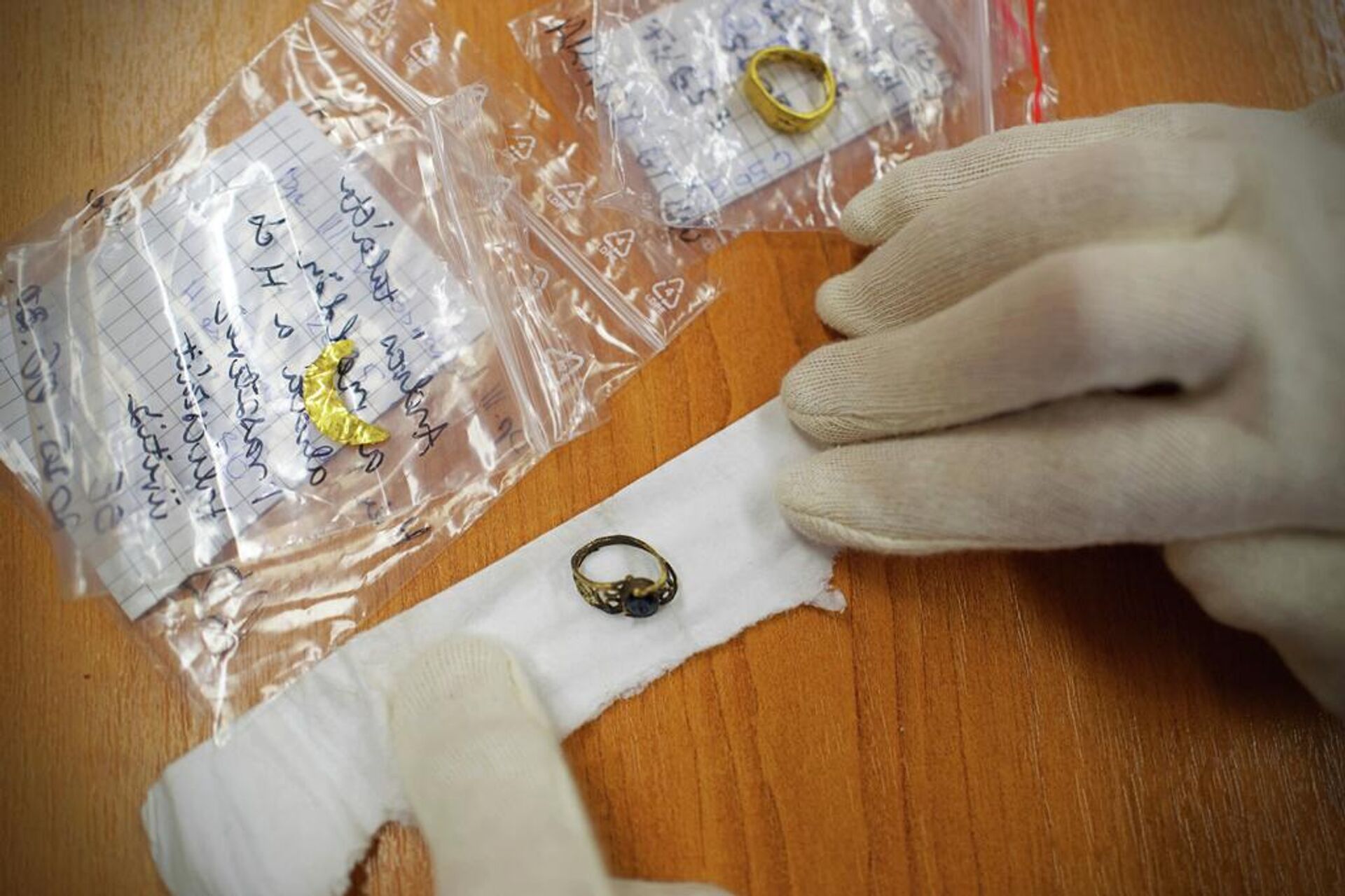 An archaeologist shows golden jewelry found at an archeological site where an intact Roman sarcophagus was unearthed, Wednesday, Nov. 19, 2025 in Budapest, Hungary. (AP photo/Bela Szandelszky) - Sputnik Türkiye, 1920, 21.11.2025