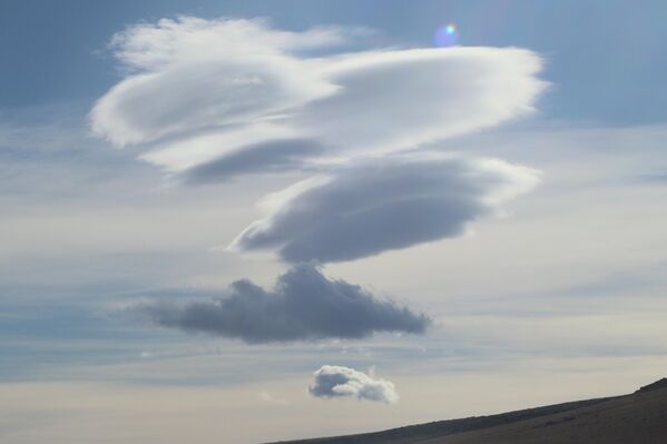Bilimsel adıyla lenticular bulut olarak bilinen mercek bulutları, rüzgarın dağ sıraları üzerinden geçerken oluşturduğu hava dalgaları sonucunda meydana geliyor. Bilimsel adıyla lenticular bulut olarak bilinen mercek bulutları, rüzgarın dağ sıraları üzerinden geçerken oluşturduğu hava dalgaları sonucunda meydana geliyor. - Sputnik Türkiye