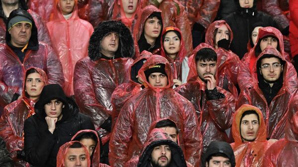 Galatasaraylı taraftarlar karşılaşmayı dağıtılan yağmurluklarla izledi.  - Sputnik Türkiye