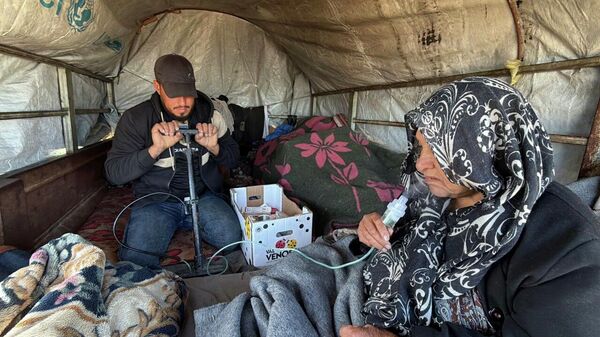 Gazze'de bir genç, hasta annesinin nefes almasını kolaylaştırmak için nebülizatör yerine bisiklet pompası kullanıyor - Sputnik Türkiye