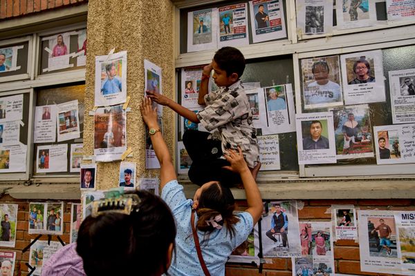 Nepal'in Katmandu kentindeki devlet hastanesinin önünde kayıp ve hayatını kaybeden kişilere ait fotoğrafların asılı olduğu duvara bir çocuk, kayıp yakınının fotoğrafını asması için bir kadına yardım ediyor - Sputnik Türkiye