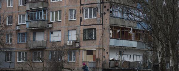 Bir kadın, Avdeyevka kentinde çatışmalar nedeniyle yıkılan çok katlı apartman binasının önünden geçiyor Bir kadın, Avdeyevka kentinde çatışmalar nedeniyle yıkılan çok katlı apartman binasının önünden geçiyor - Sputnik Türkiye