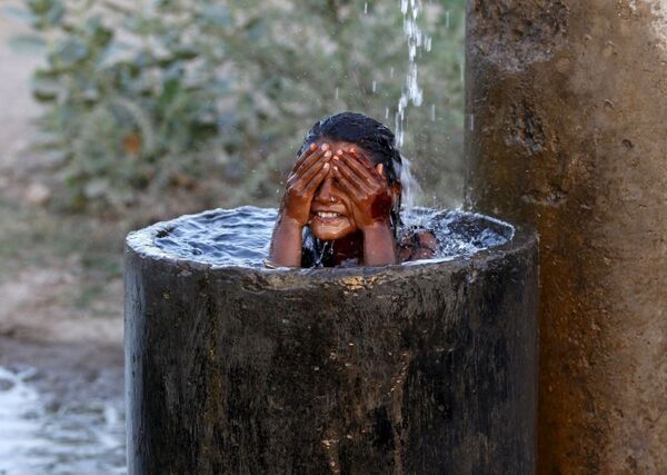 Aşırı sıcaklıkların yaşandığı Hindistan'da bir kız serinlemek için yıkanıyor - Sputnik Türkiye