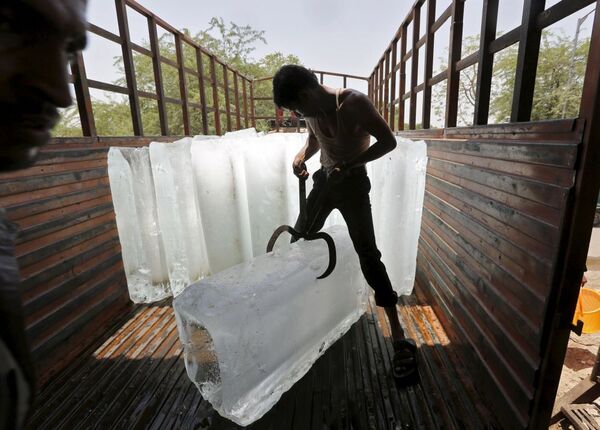 Aşırı sıcaklıkların yaşandığı Hindistan'da bir işçi buz kalıbını parçalıyor - Sputnik Türkiye
