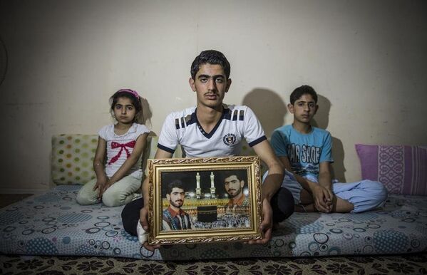 Evlerinin yıkılmasının ardından apar topar Türkiye’ye göç eden Hüseyin ailesinin elinde yalnızca babalarının bir fotoğrafı kalmış. - Sputnik Türkiye