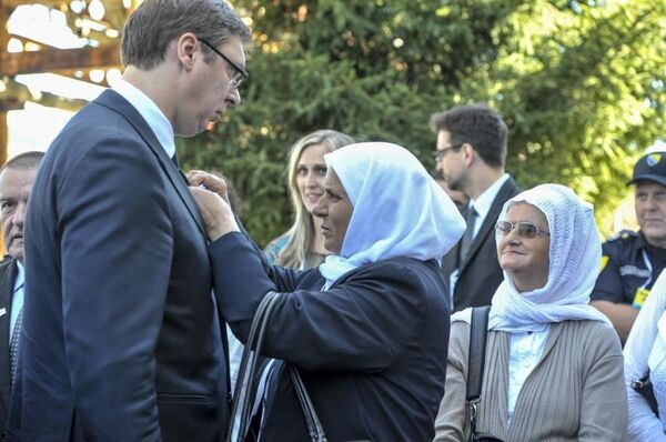 Srebrenitsa Anneleri Derneği Başkanı Hatice Mehmedoviç, anma törenine katılan Sırbistan Başbakanı Vuçiç'in yakasına, kurbanlar anısına hazırlanan çiçeği taktı. - Sputnik Türkiye