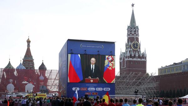 Officials, participants of a soccer exhibition under-16 tournament and spectators listen to Russia's President Vladimir Putin delivering a speech via a video link from Sochi, during a ceremony marking 1,000 days until the beginning of the 2018 FIFA World Cup in Red Square in central Moscow, Russia, September 18, 2015 - Sputnik Türkiye